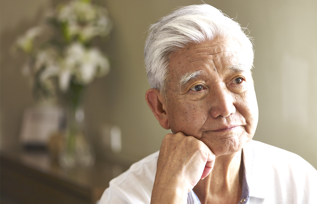 白髪の男性 肘をついて憂う表情