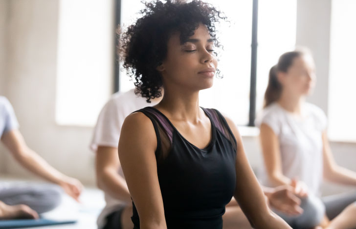ヨガのクラスで目を閉じて集中する女性