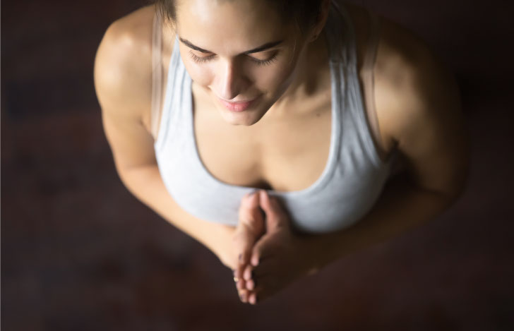 胸の前で手を合わせて目を閉じるる女性