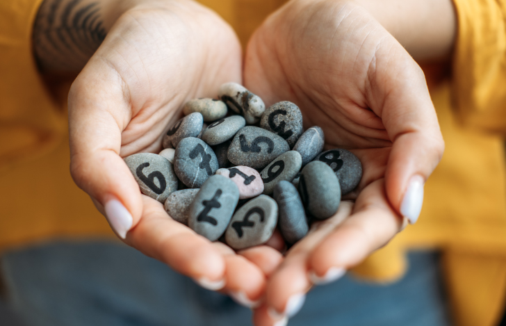 数字が描かれた小石を両手で掬い上げる人の手元