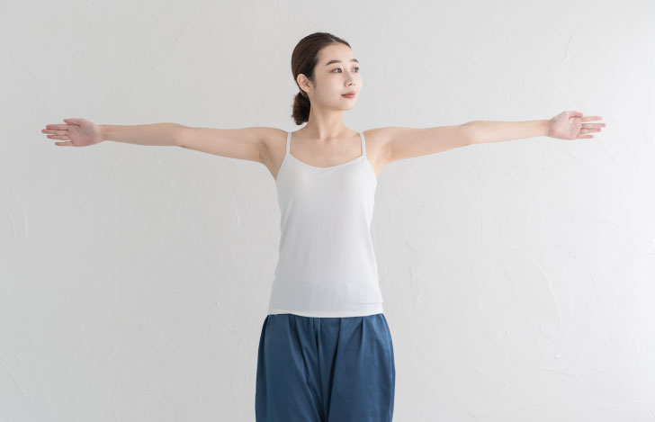 両腕を肩の高さで広げる女性