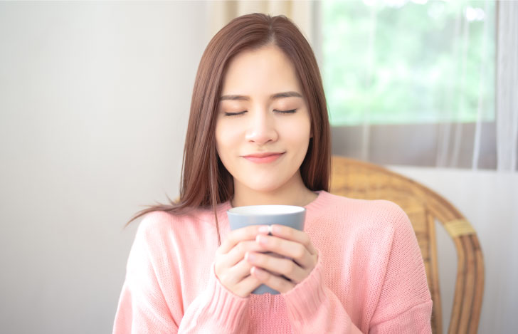 目を閉じてお茶を味わう女性