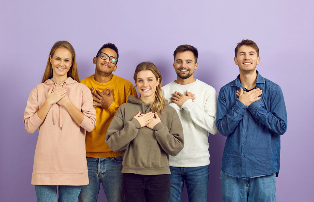 複数の男女が胸に手を当てて笑っている