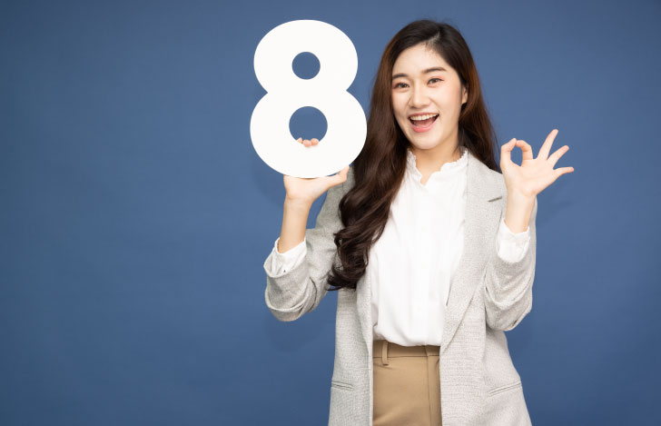 数字の8の字のオブジェを持ち笑顔でポーズをとる女性