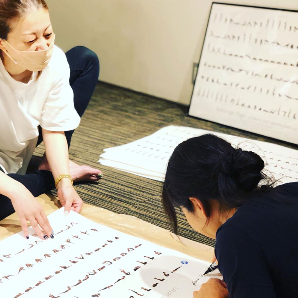 ヨーコ・フジワラと共にポスターにサインをしている様子