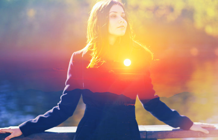 屋外で手すりにもたれながら物思いに耽る女性と夕日のダブルイメージ