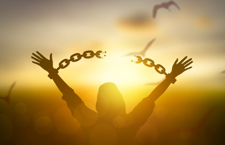 空に向かって両手をあげて繋がれた鎖をちぎる人のシルエット