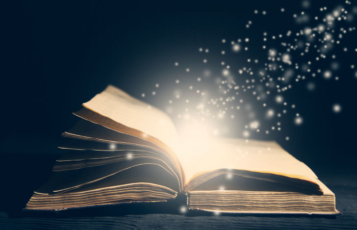 机の上で開かれた古い本と飛び出す光