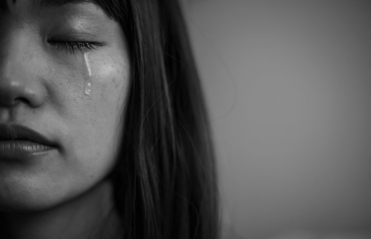 目を閉じて涙を流す女性の顔