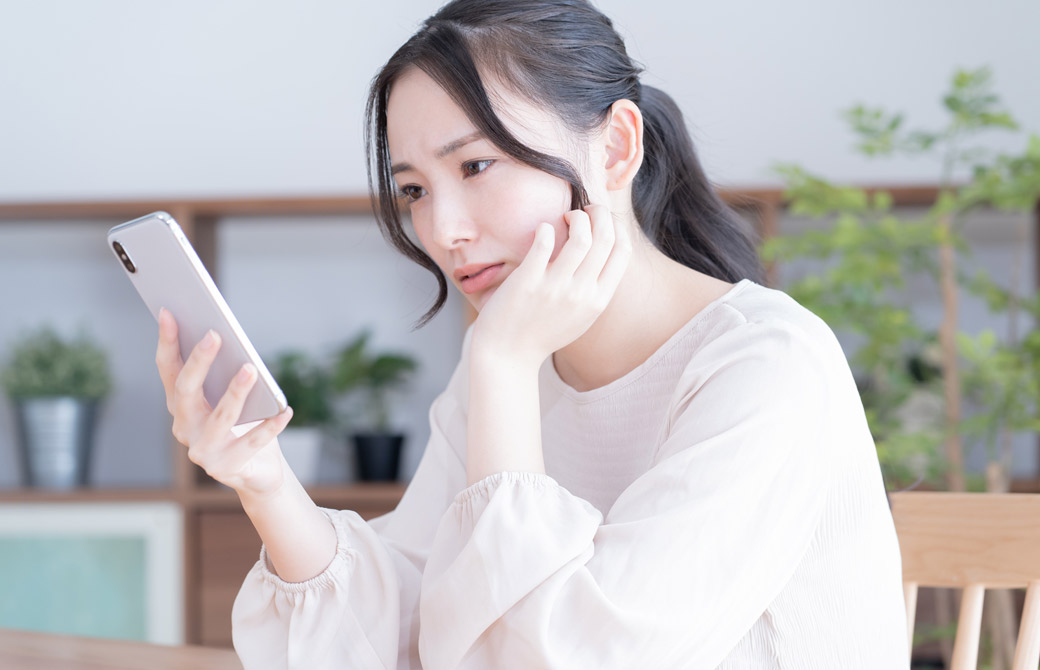スマホを眺めて不安な様子の女性