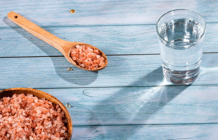 器に盛られた岩塩とスプーンですくったその一部とコップに入った水