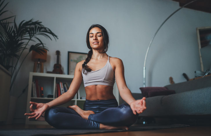 室内で瞑想するヨガウェアを着た女性