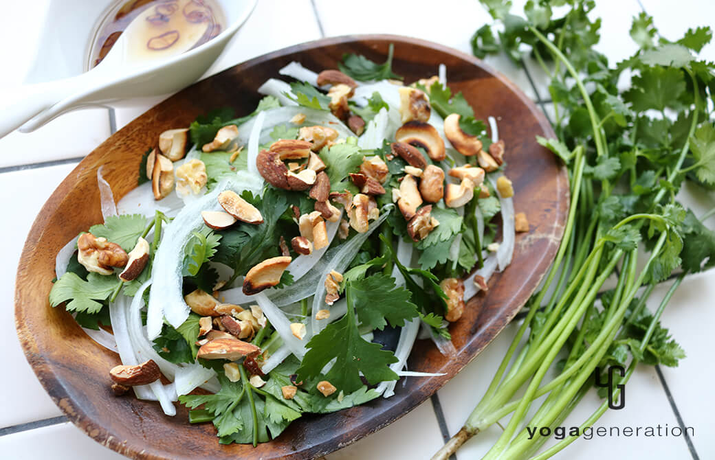 木のお皿に盛り付けた新タマネギとパクチーのアジアン・ナッツサラダ