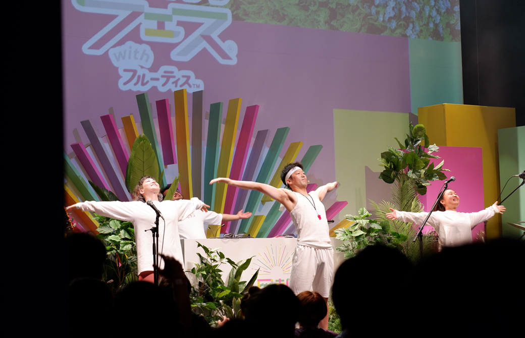 ステージでラジオ体操をする3人