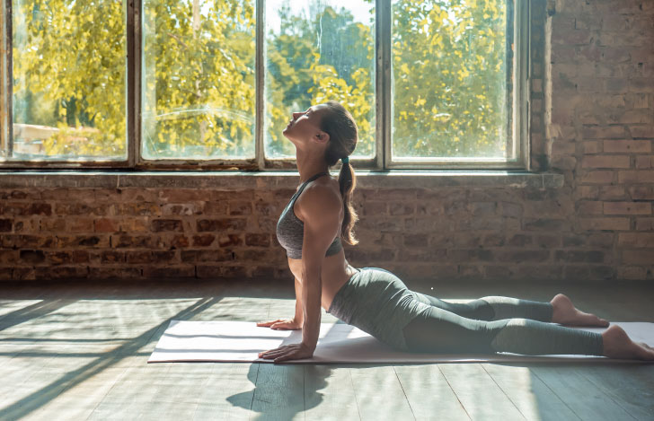 室内の窓辺でヨガを行う女性