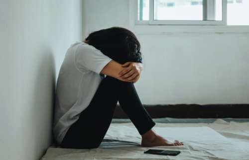 膝をかかえて座る女性