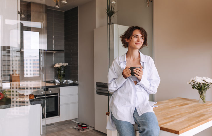 室内でマフカップを手にくつろぐ様子の女性