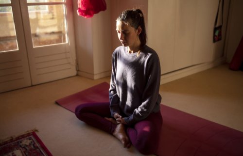 部屋の中で目を閉じて座る女性