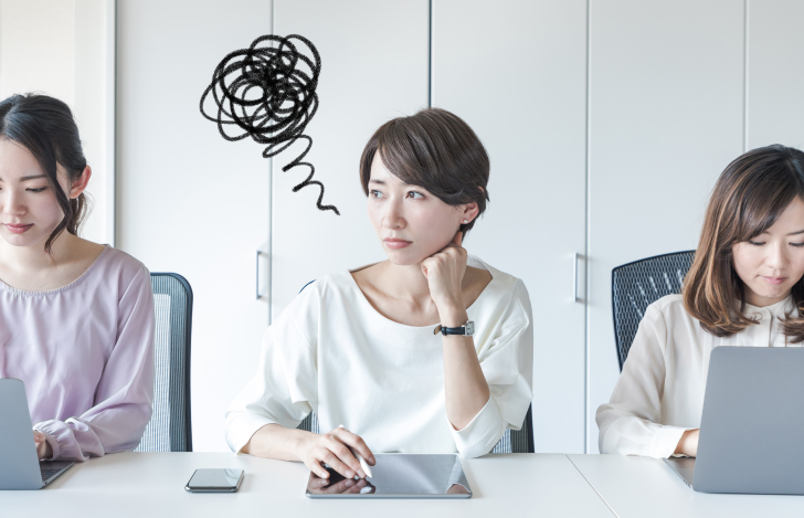 オフィスで頬杖をついて思い悩んだ表情の女性