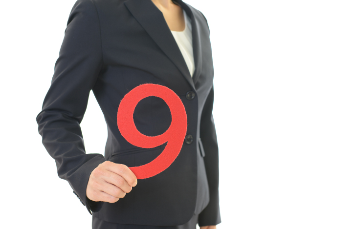 手に数字の9を持ったスーツ姿の女性