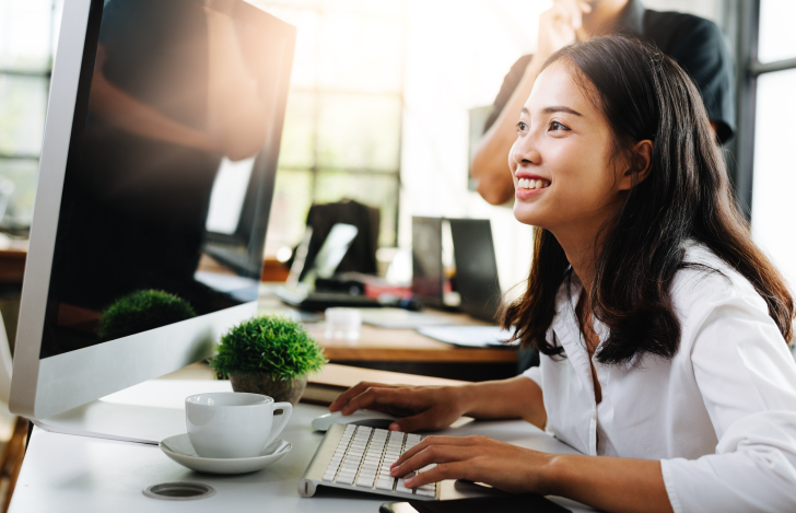 笑顔でパソコンのモニターに向かう女性