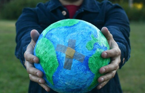 絆創膏の貼られた地球儀を両手で包む様子