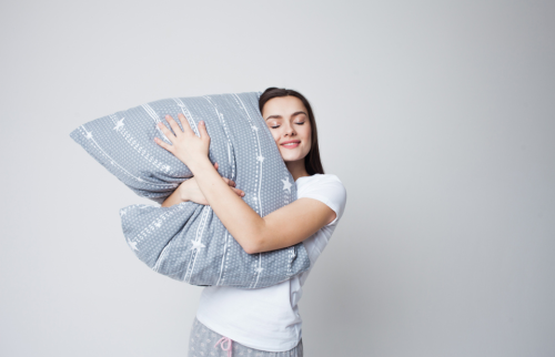 枕を抱いてほほ笑む美しい女性