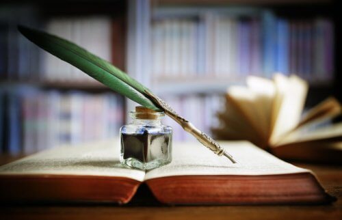 広げた本の上に乗ったインクと羽ペン