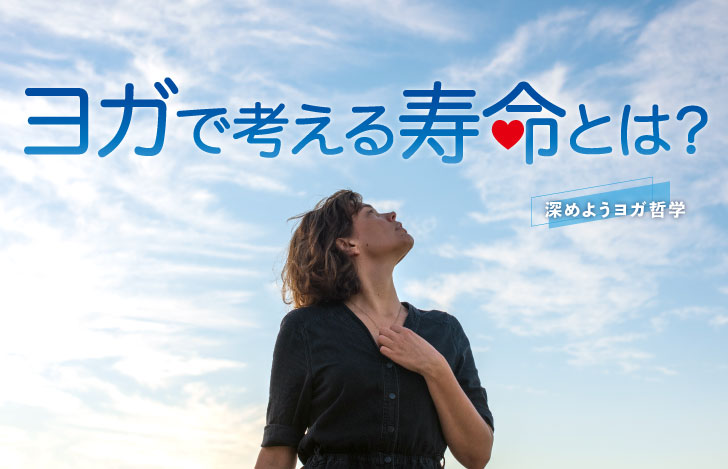 手を胸に当てて空を見上げる黒いカーディガン姿の女性