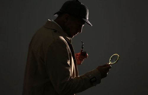 虫眼鏡とパイプを持つ帽子をかぶった男性