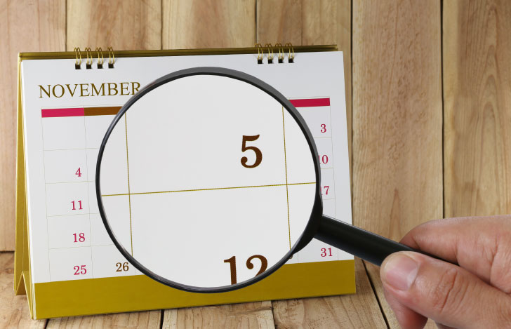 立て掛けカレンダーに虫眼鏡を当てて数字を拡大する様子