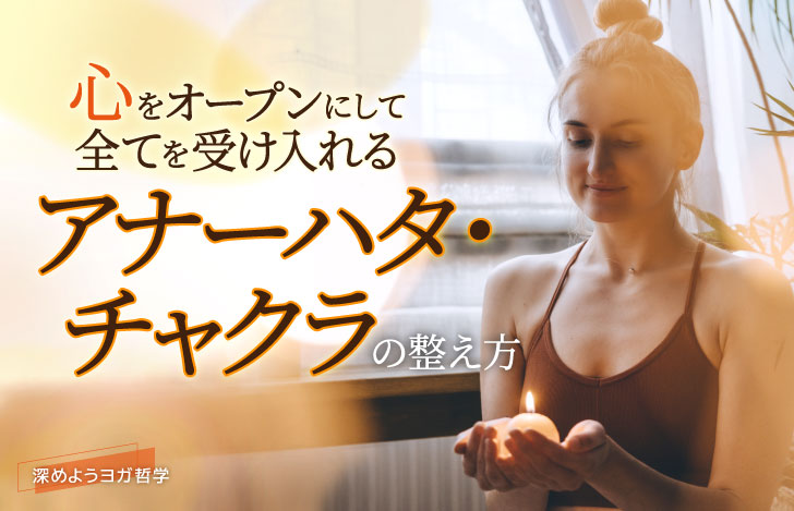 室内でキャンドルを手に炎を見つめるヨガウェアを着た女性