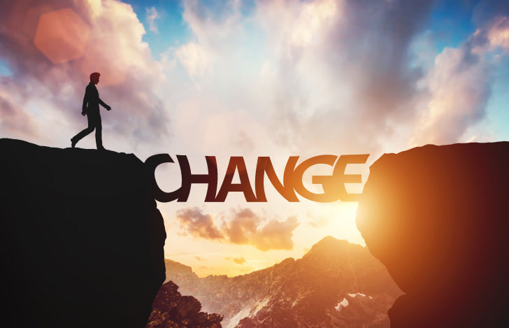 崖をtunakuCHANGEの文字とそれを渡ろうとする男性のシルエット