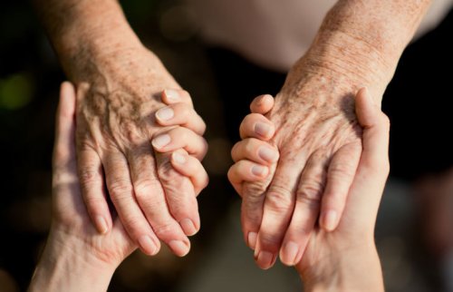 しわのある手をにぎるようにつなぐもう1つの手