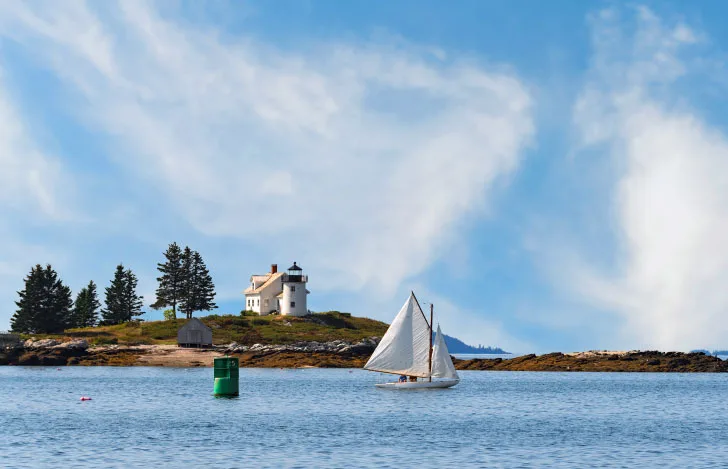 大海原の岸の近く走るヨットと青空