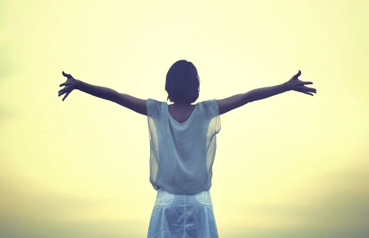 両手を広げて立つ女性の後ろ姿