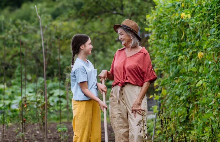 祖母と孫が畑で目を見合わせて笑顔で立つ様子