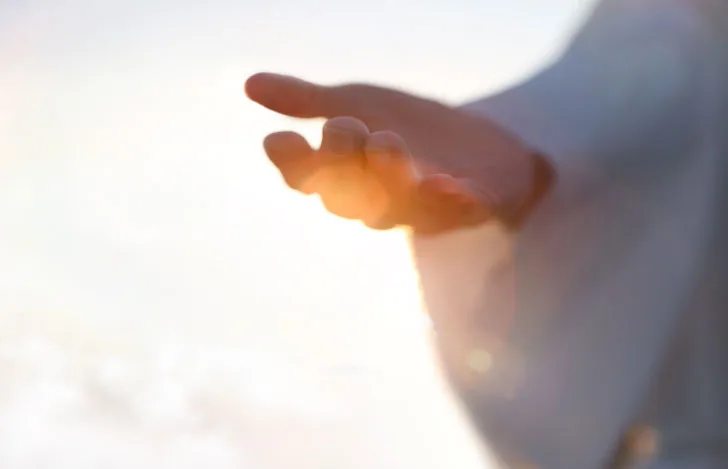 白いゆったりとした服を身につけた人の差し出された手