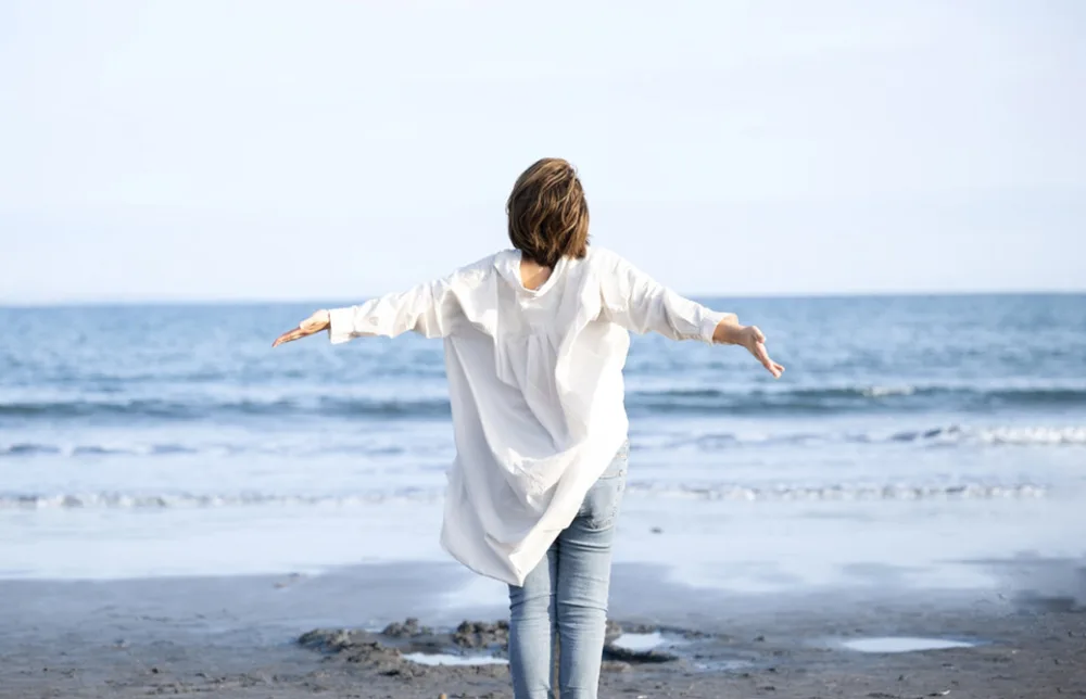海の前で女性が胸を広げている