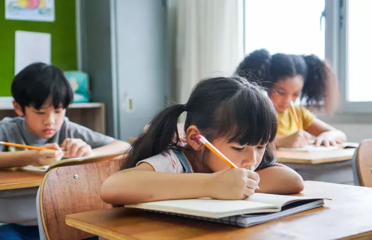 机に座って教科書をじっと見つめる女の子