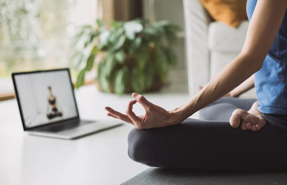 女性がパソコンの前でヨガをしている
