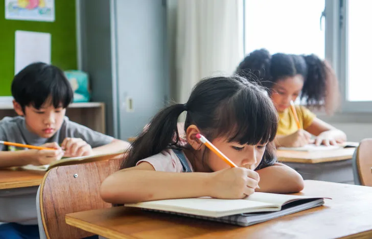 机に座って教科書をじっと見つめる女の子