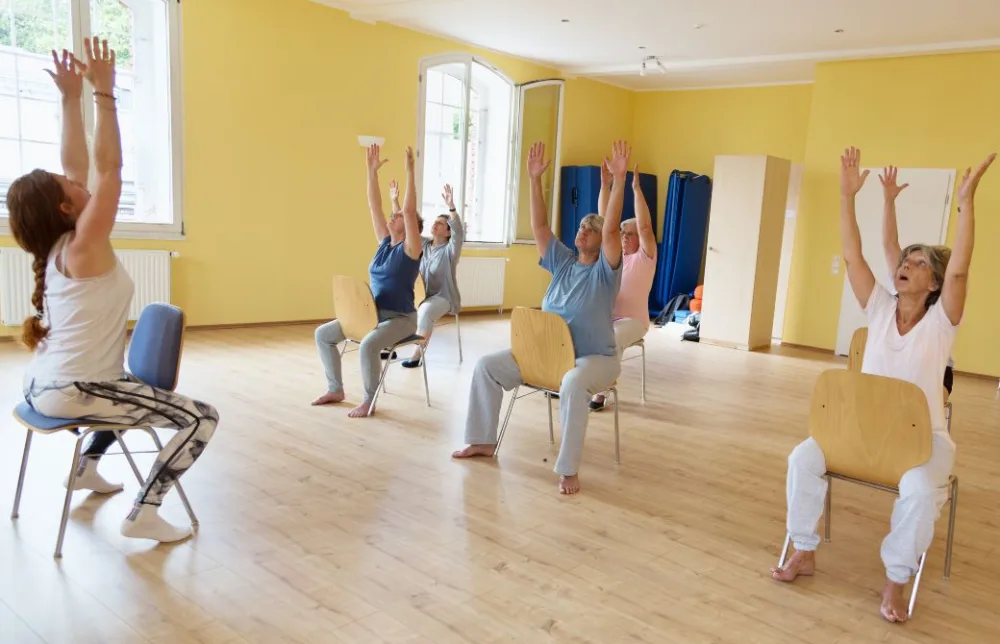 チェアヨガをしている複数のシニアと指導する講師