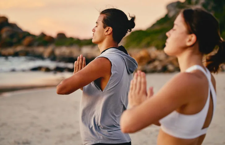 太陽に向かって胸の前で合掌する男女