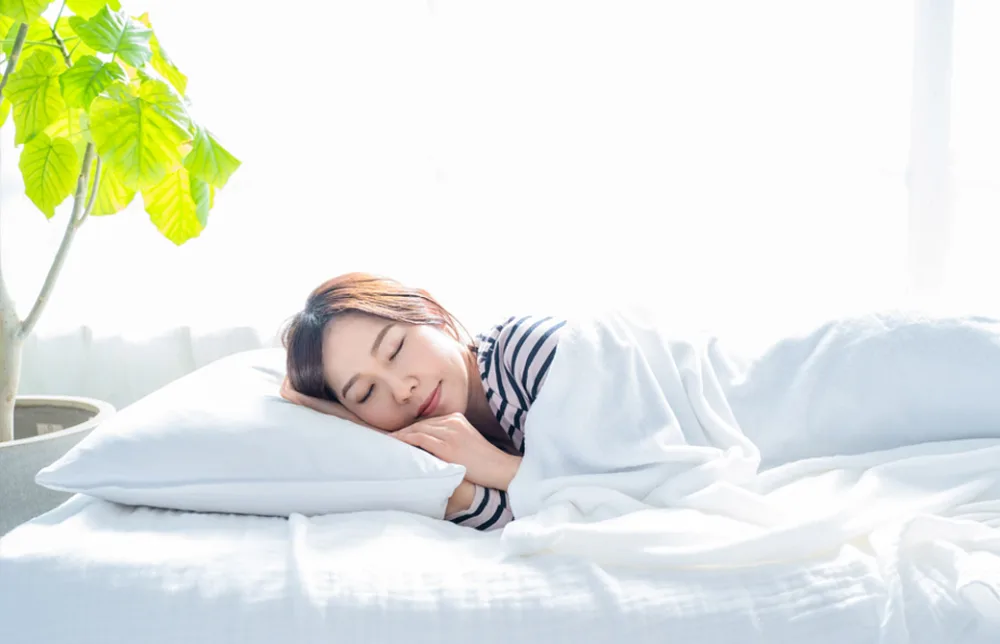 明るいシンプルな部屋のベッドで眠る女性