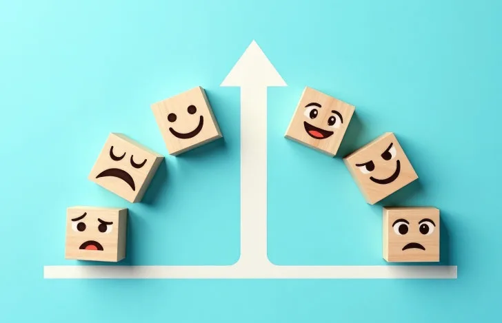 人の表情が描かれた木のオブジェと矢印のグラフィック