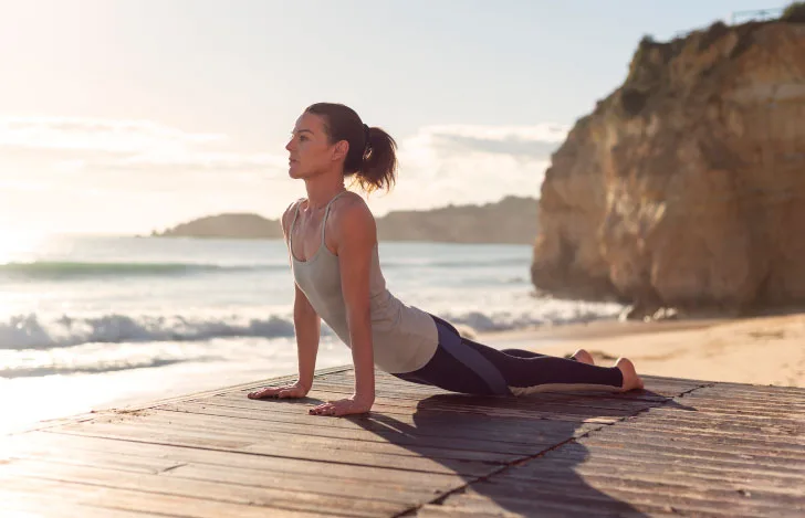 朝焼けに向かって太陽礼拝をする女性