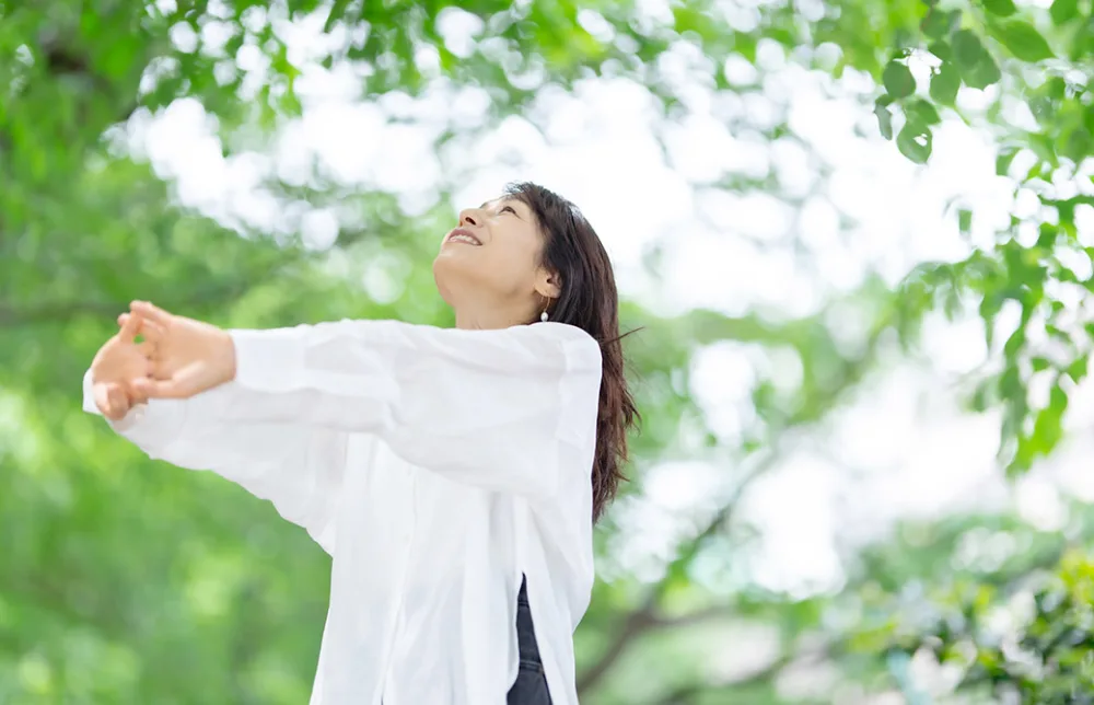 40代50代の女性が緑の中で伸びをしている