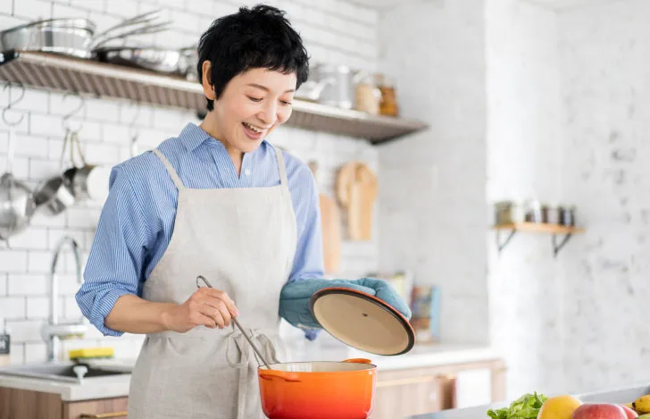 キッチンで笑顔で料理する女性