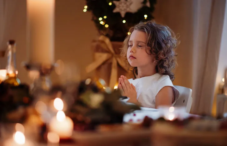 食卓で目を閉じて祈る少女